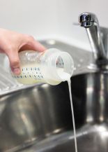 image is unused breastmilk being poured into a sink to discard it 